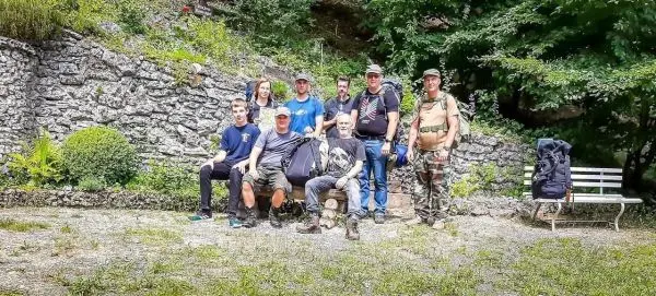 Gruppe von Personen mit Rucksäcken und Ausrüstung auf einem Platz in der Natur