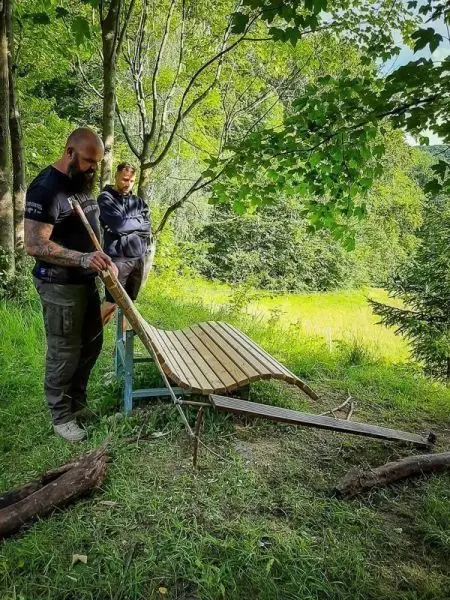 Holzplattform wird mit einem Stock stabilisiert, während eine Person beobachtet