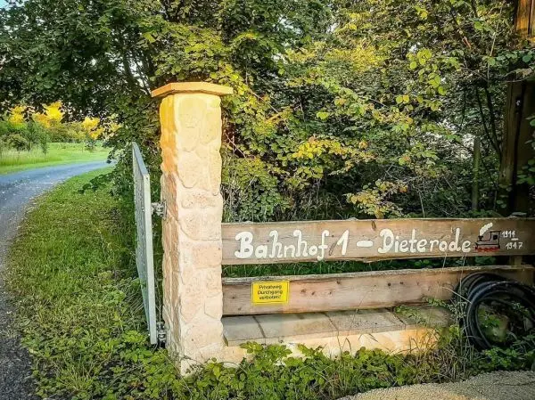 Holzschild mit der Aufschrift &amp; quot; Bahnhof 1 - Dieterode&amp; quot; an einem Eingangstor