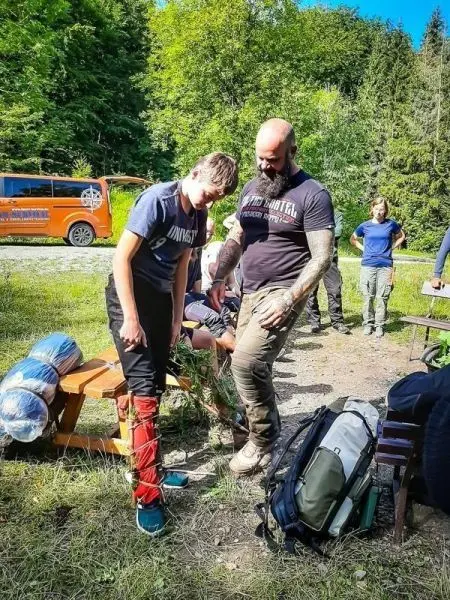 Junge übt das Anlegen einer improvisierten Schiene an einem Bein