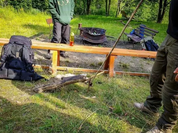 Person hält Stock über Holzstück beim Kochen im Freien