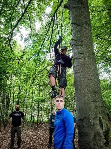 Person klettert an einem Seil hoch, während andere zuschauen