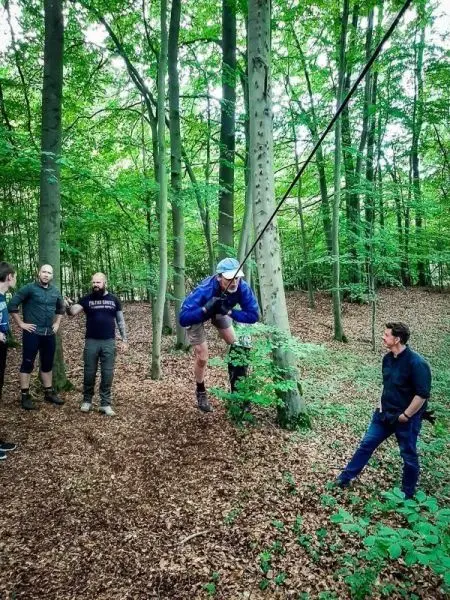 Teilnehmer nutzt Seil zur Querung zwischen Bäumen im Wald