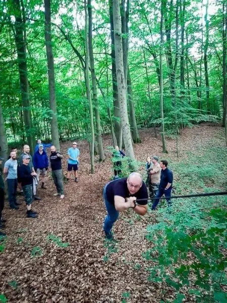 Teilnehmer nutzt selbstgebaute Seilbrücke zur Überquerung einer Lichtung im Wald