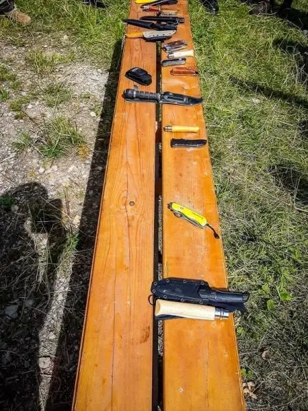 Werkzeuge und Messer liegen auf einer Holzbank im Freien