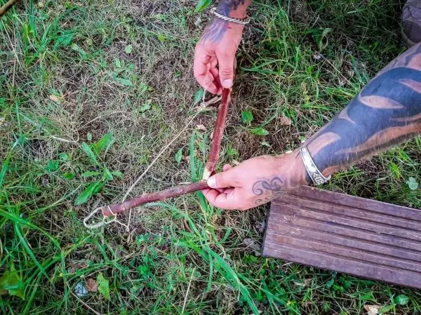 Zwei Holzstücke werden mit einer Schnur verbunden, um eine Falle zu konstruieren