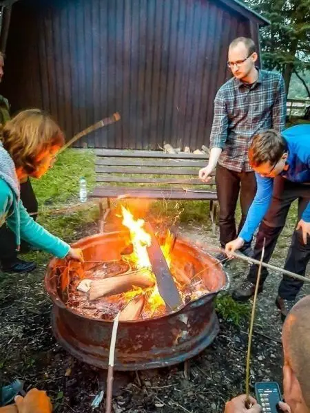 Zwei Personen fügen Holzscheite in ein Feuer in einem Metallring