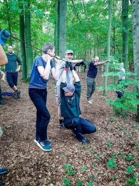 Zwei Personen ziehen an einer improvisierten Trage durch den Wald