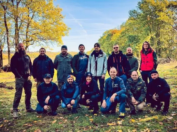 Gruppe von Personen in Outdoor-Bekleidung steht im Freien zwischen Bäumen