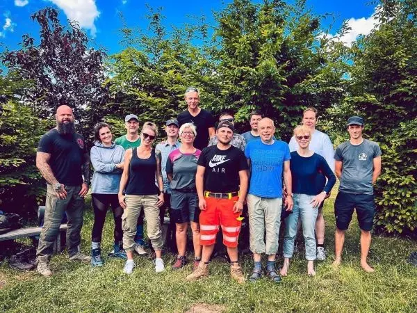 Gruppe von Personen steht vor einer Hecke in einem Garten
