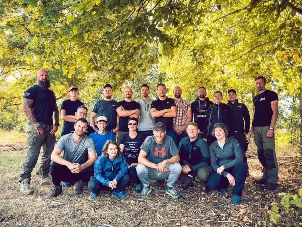 Gruppe von Teilnehmern in Outdoor-Bekleidung unter Bäumen im Wald