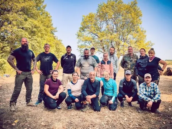 Gruppierung von Personen im Freien, umgeben von Bäumen und Grasboden