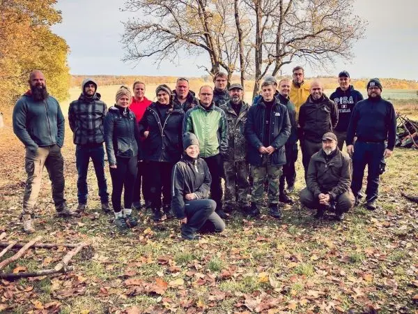 Gruppierung von Personen im Freien, umgeben von Bäumen und herbstlichem Laub