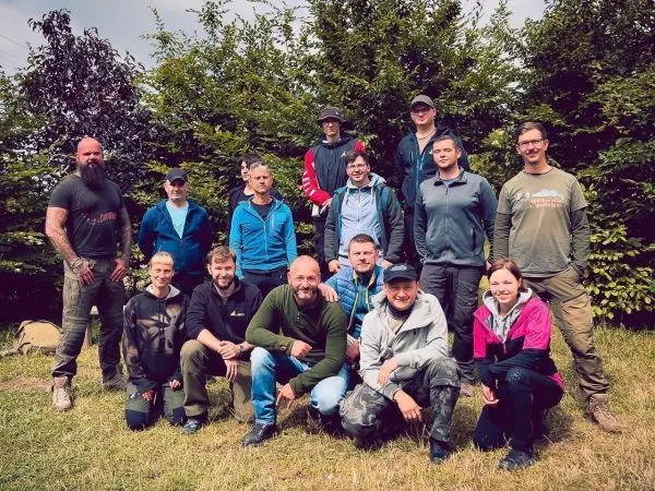 Gruppierung von Personen in Outdoor-Bekleidung vor einer Hecke
