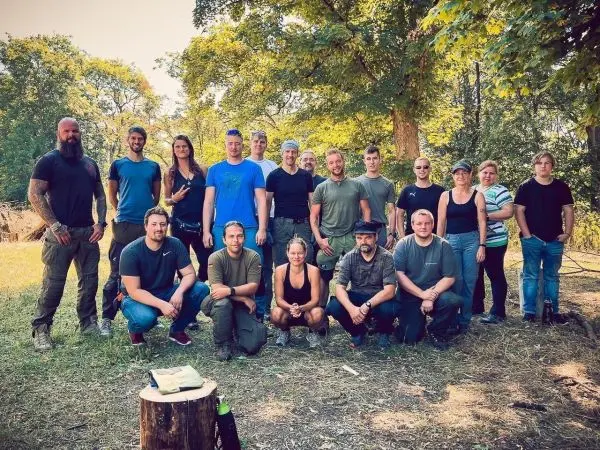 Gruppierung von Teilnehmern auf einer Wiese, umgeben von Bäumen und Natur