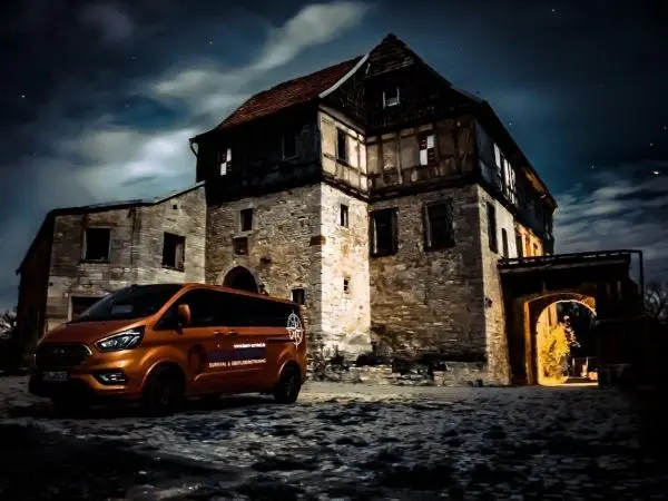 Oranger Transporter steht vor einem alten, steinernen Gebäude bei Nacht