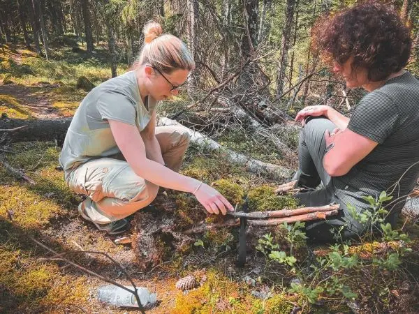 Zwei Personen bauen eine improvisierte Falle aus Ästen im Wald