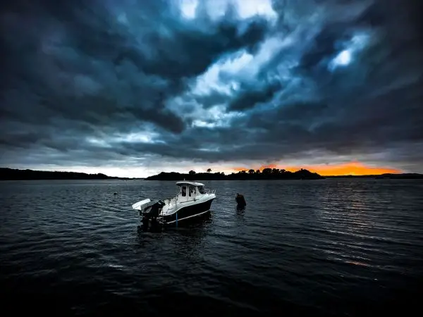 Boot liegt im Wasser, während eine Person im seichten Wasser steht