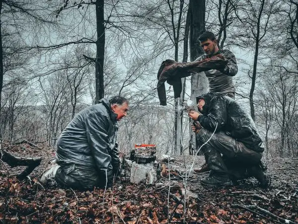 Drei Personen bereiten eine Feuerstelle im Wald vor