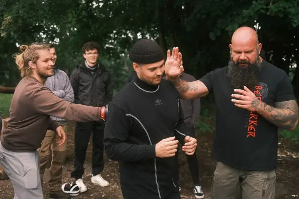 Ein Mann demonstriert eine Technik zur Selbstverteidigung, während andere zuschauen