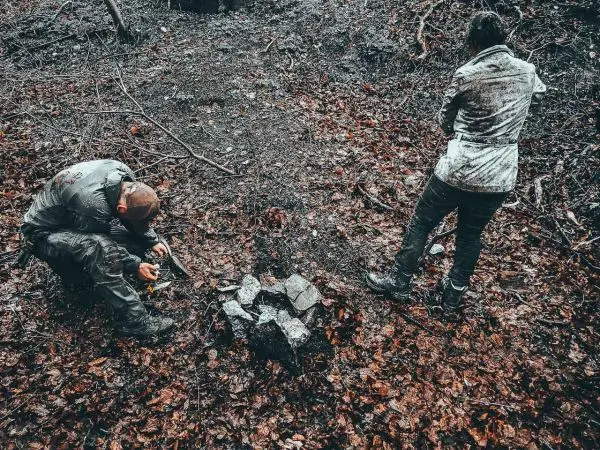 Feuerstahl entzündet Zunder neben einem Steinkreis im Wald