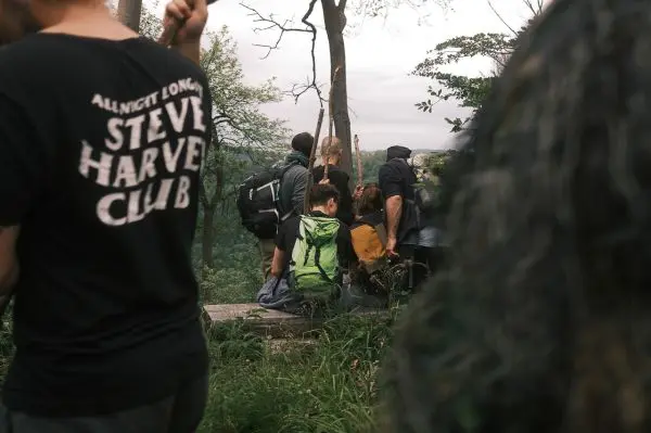 Gruppe mit Rucksäcken sitzt auf einer Holzbank im Wald