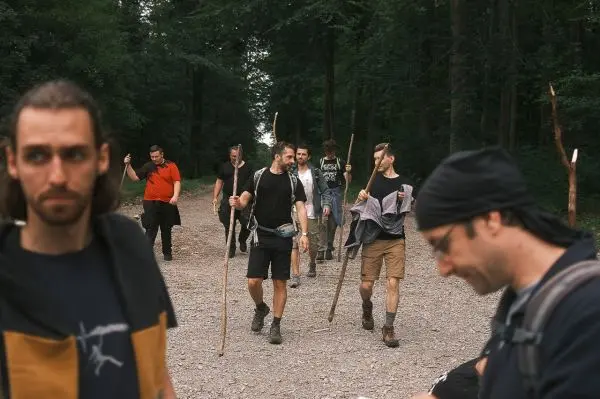 Gruppe von Personen geht mit Stöcken auf einem Waldweg beim Überlebenstraining