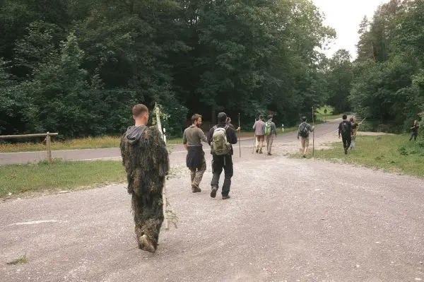 Gruppe von Personen mit Rucksäcken geht auf einem Weg durch den Wald