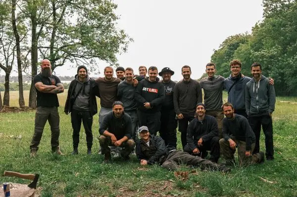 Gruppe von Personen posiert auf einer Wiese vor Bäumen