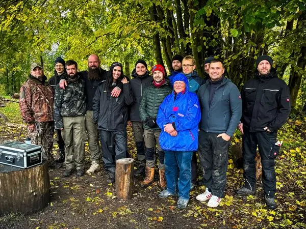 Gruppe von Personen posiert im Freien vor Bäumen beim Outdoortraining