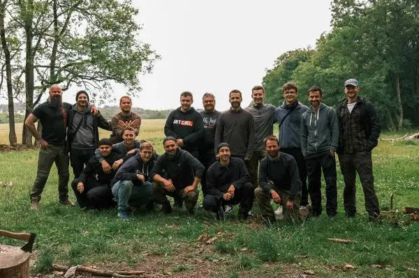 Gruppe von Personen steht auf einer Wiese, umgeben von Bäumen