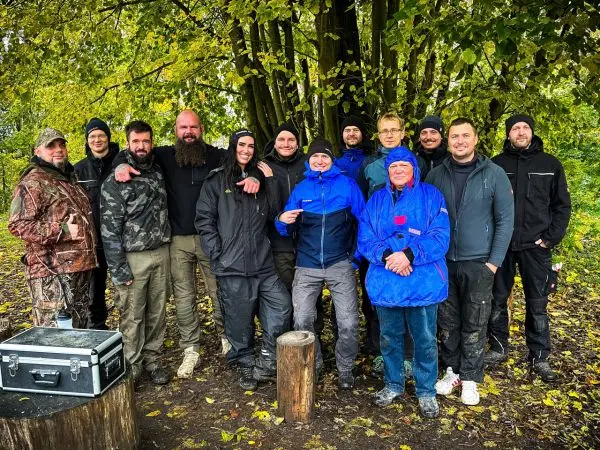 Gruppe von Personen steht lächelnd unter einem Baum im Freien