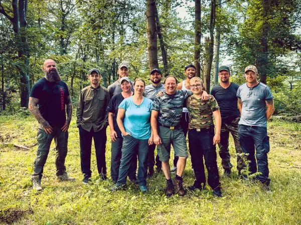 Gruppe von zehn Personen steht im Wald zusammen