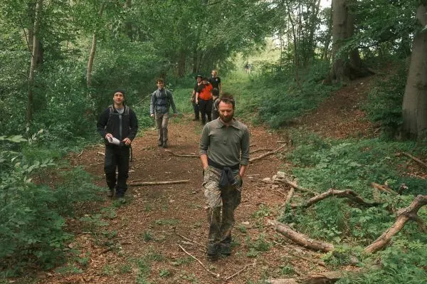 Gruppe wandert auf einem Waldweg zwischen Bäumen und Sträuchern