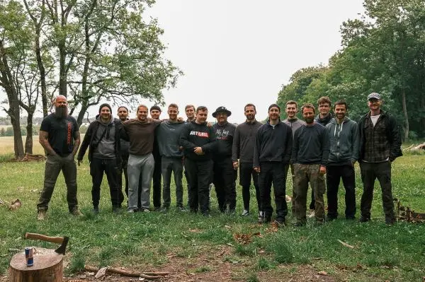 Gruppierung von Personen im Freien, umgeben von Bäumen und Wiese