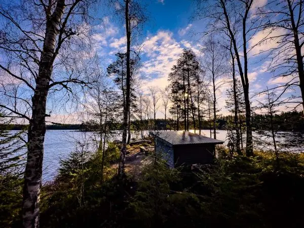 Holzhütte am Ufer eines Sees, umgeben von Bäumen und Wasser