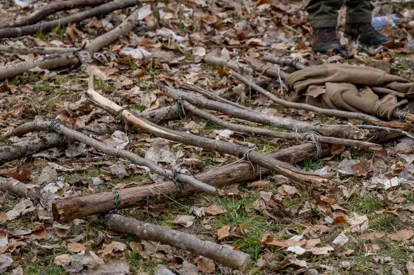 Holzkonstruktion aus Ästen mit Schnüren auf Laubuntergrund