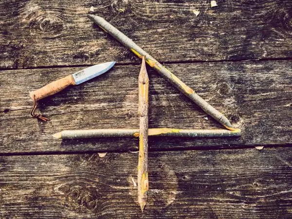 Holzkonstruktion aus Ästen und einem feststehenden Messer auf Holzuntergrund