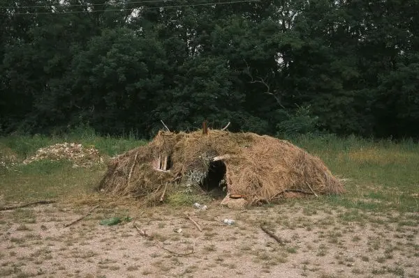 Hütte aus Gras und Ästen in einer Wiese