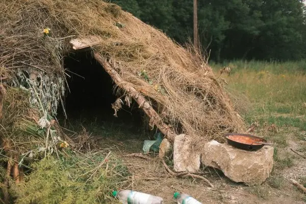 Hütte aus Naturmaterialien mit Steinen und einer Pfanne davor