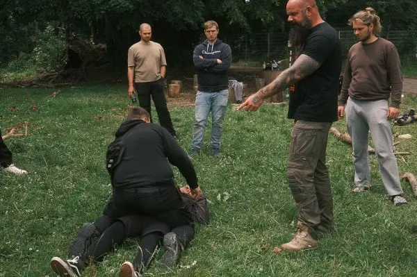 Person demonstriert eine Technik auf dem Boden, umgeben von Zuschauern