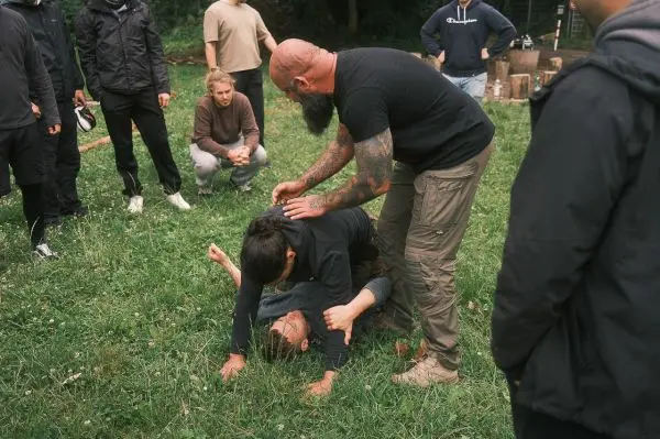 Person demonstriert eine Technik auf einer anderen Person im Gras