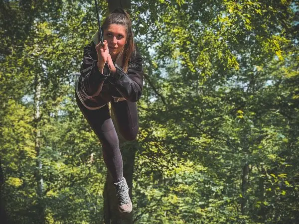 Person schwingt an einem Seil zwischen Bäumen im Wald