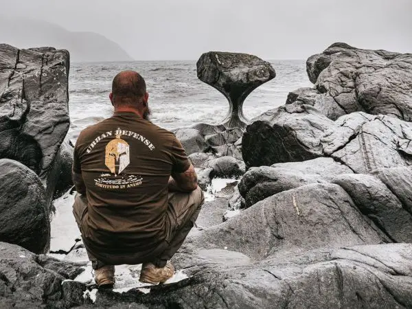 Person sitzt auf Felsen und betrachtet das Meer