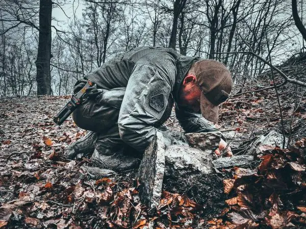Person untersucht den Boden zwischen Steinen im Wald