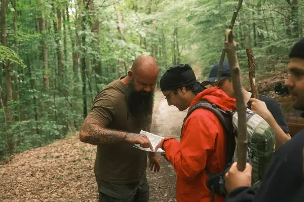 Person zeigt auf eine Karte, während andere zuschauen im Wald