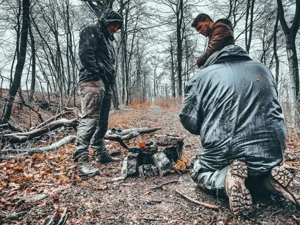 Personen beobachten Feuerstelle im Wald beim Survival Training