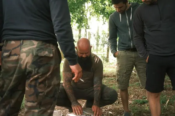 Personen betrachten eine Karte im Wald beim Überlebenstraining