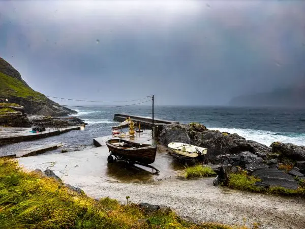 Zwei Boote liegen an einem Steg, umgeben von steiniger Küstenlandschaft