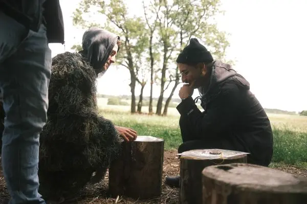 Zwei Personen sitzen auf Baumstümpfen und betrachten gemeinsam ein Objekt